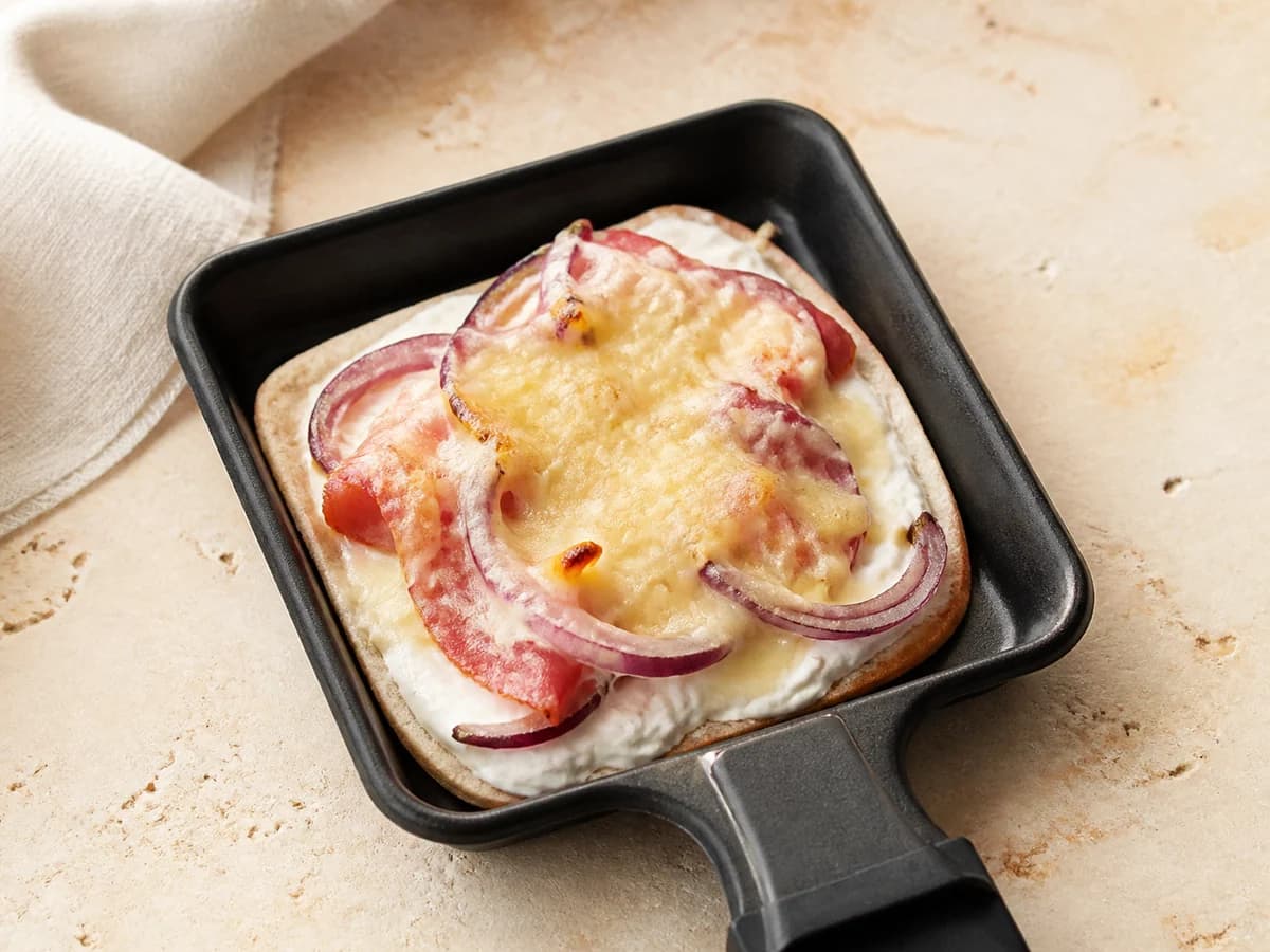 Knuspriges Flammkuchen-Pfännchen mit Crème fraîche, Zwiebeln und Speck